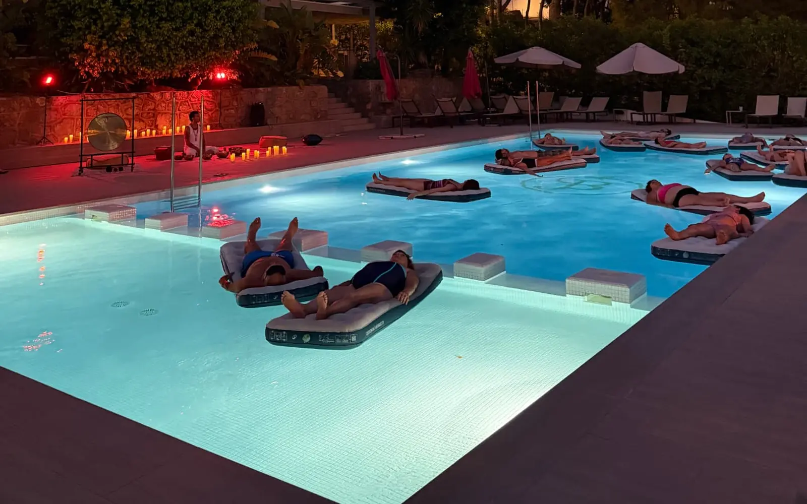 Sesión de sound healing con gong al atardecer, con personas flotando en la piscina de Bosque.